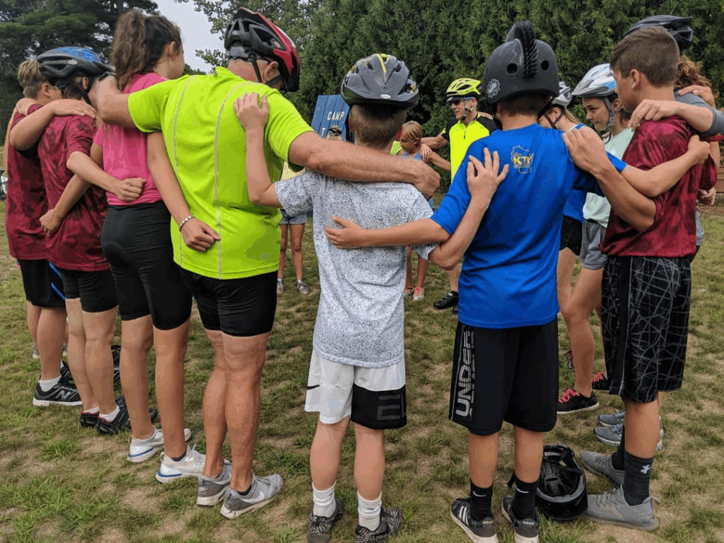 Youth pilgrims huddled in prayer during the Youth Bike Run to Camp Tekakwitha, reflecting on faith and fellowship supported by the Catholic Foundation grant.