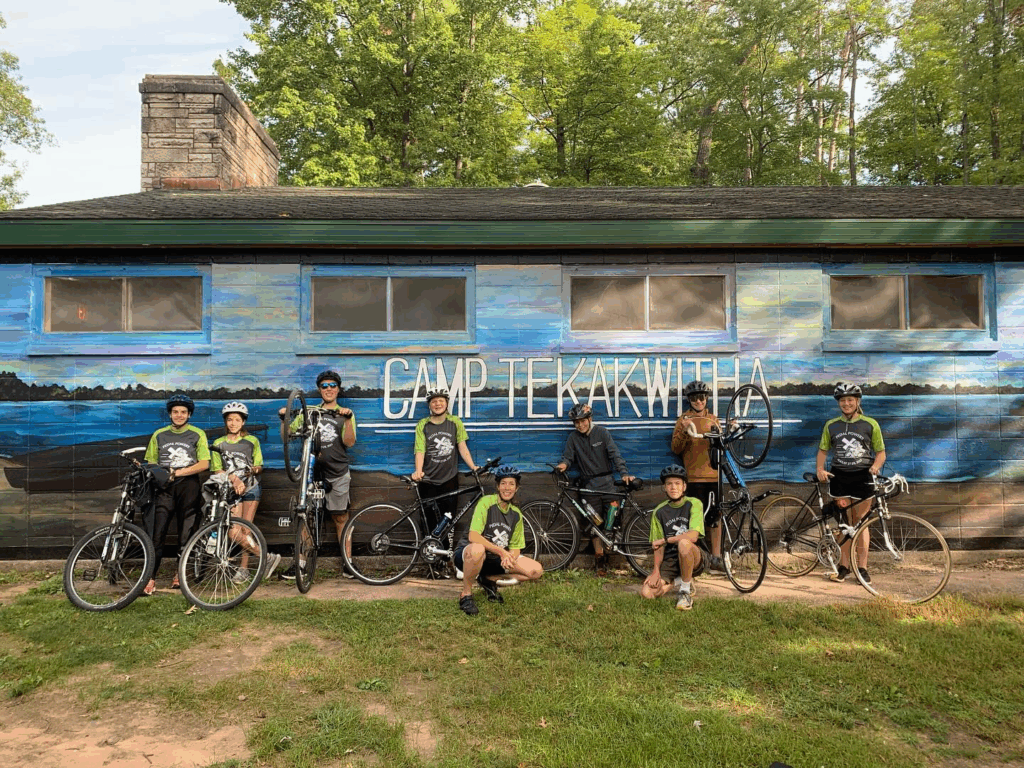 Catholic youth smiling together at Camp Tekakwitha after completing the 50-mile bike ride, celebrating faith and community made possible through donor support.